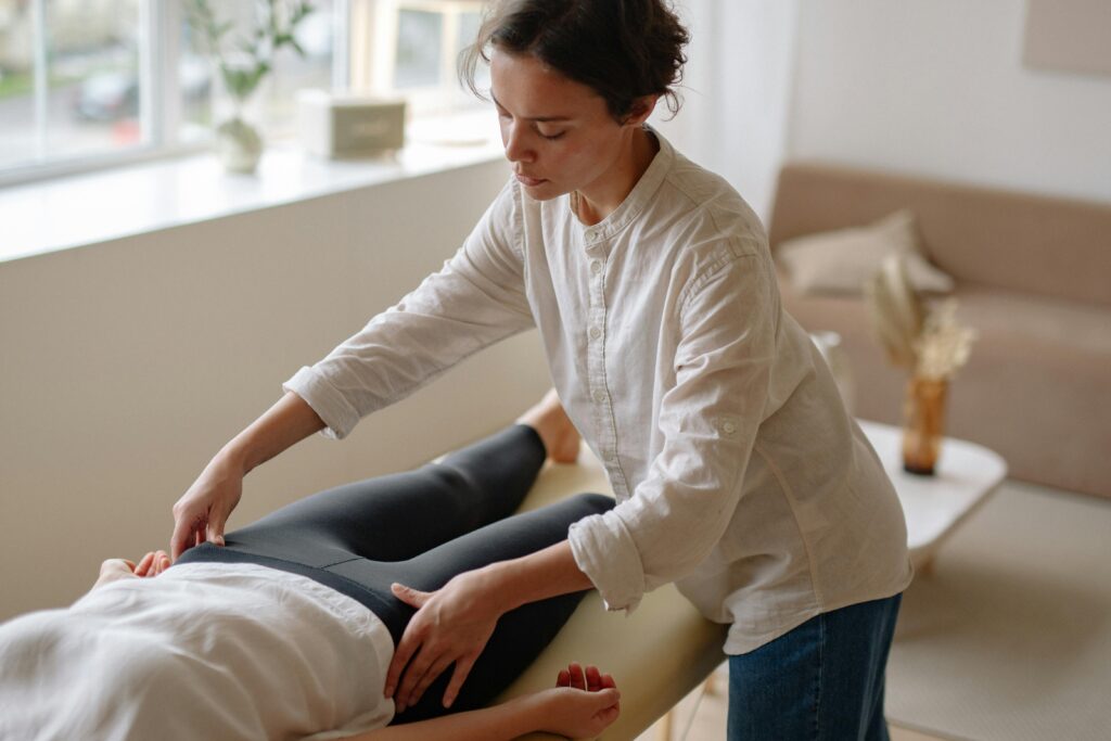 A massage therapist provides care to a lying patient in a tranquil indoor setting.