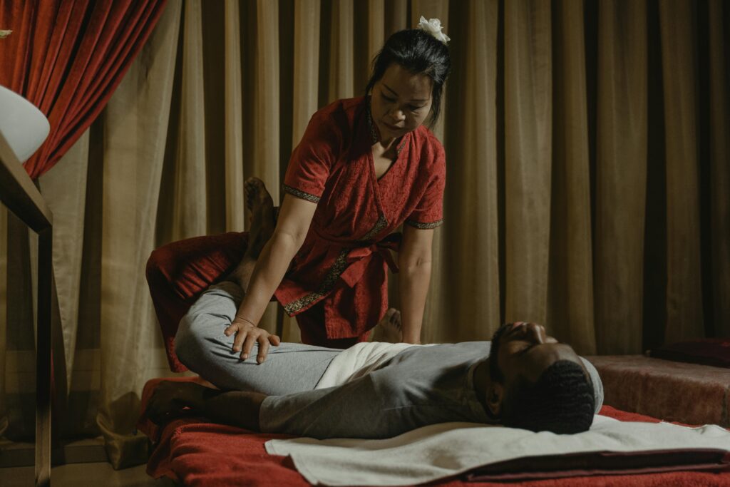 Professional therapist performing leg stretch on client in a serene massage room setting.